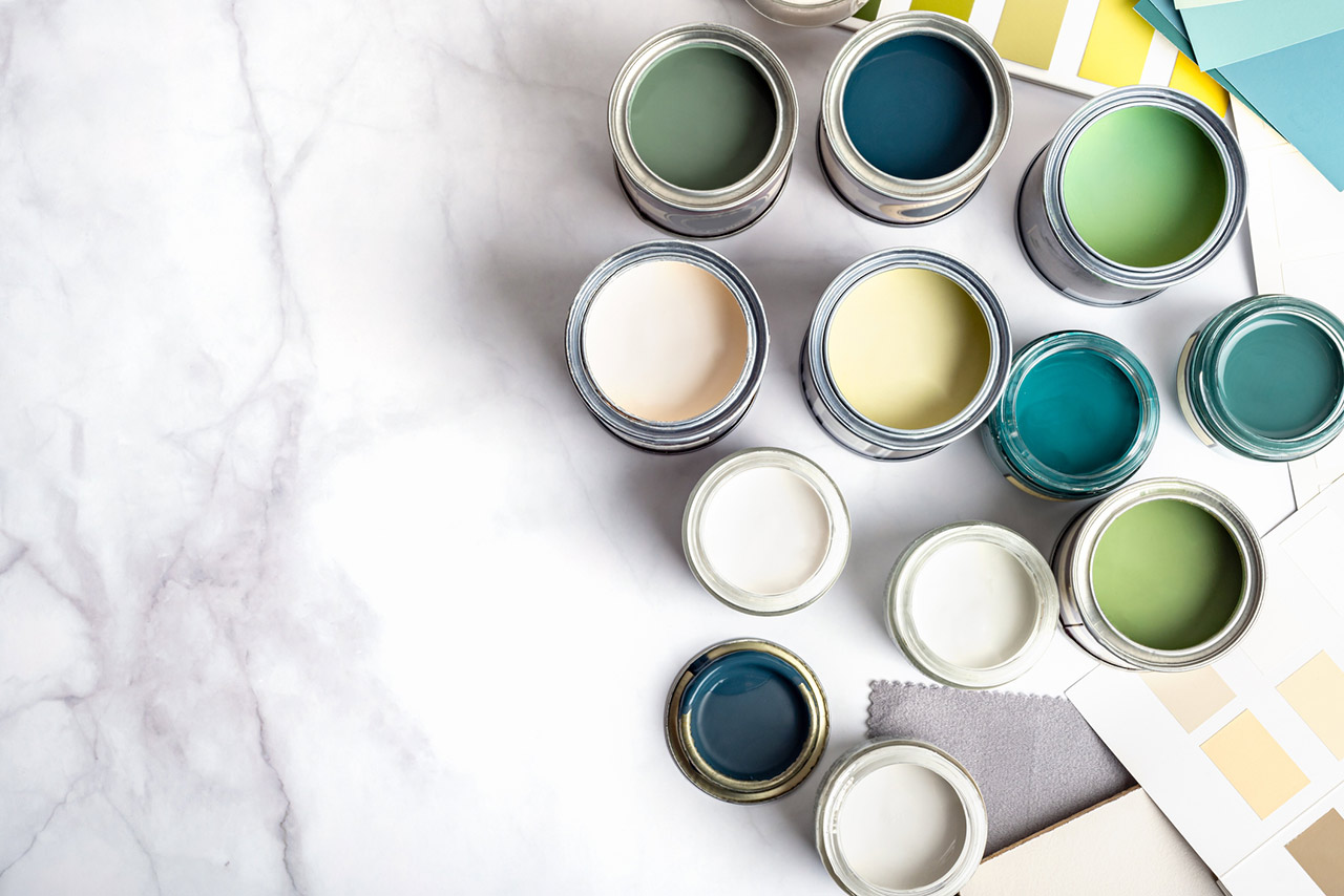 Tiny sample paint cans during house renovation, process of choosing paint for the walls, different green and beige colors, color charts on marble background
